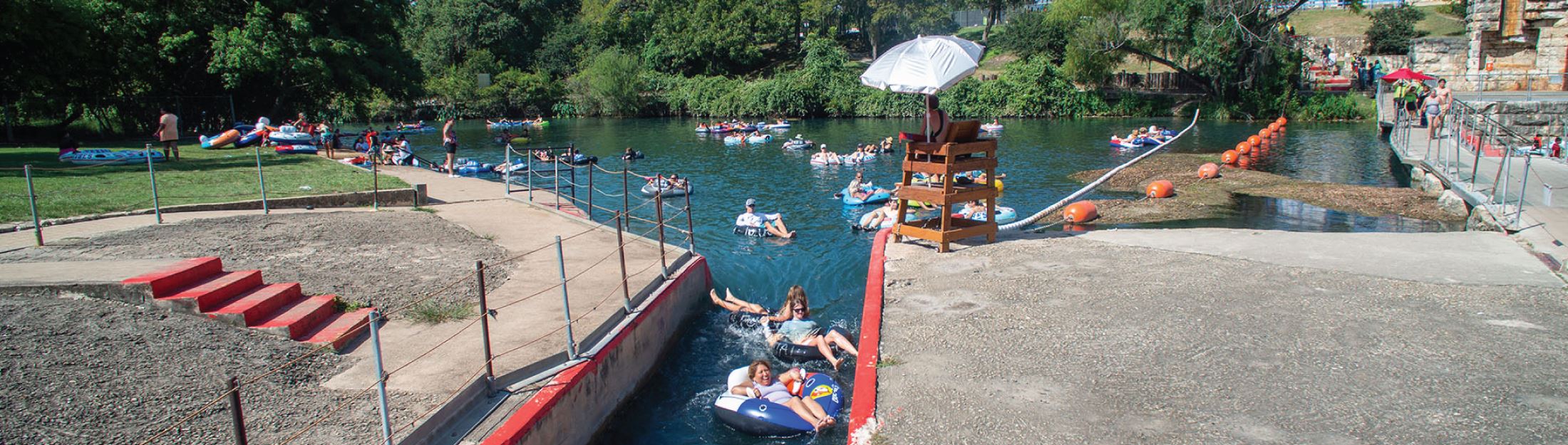 Tubers are pushed out of the Tube Chute and into the open water on the Comal River