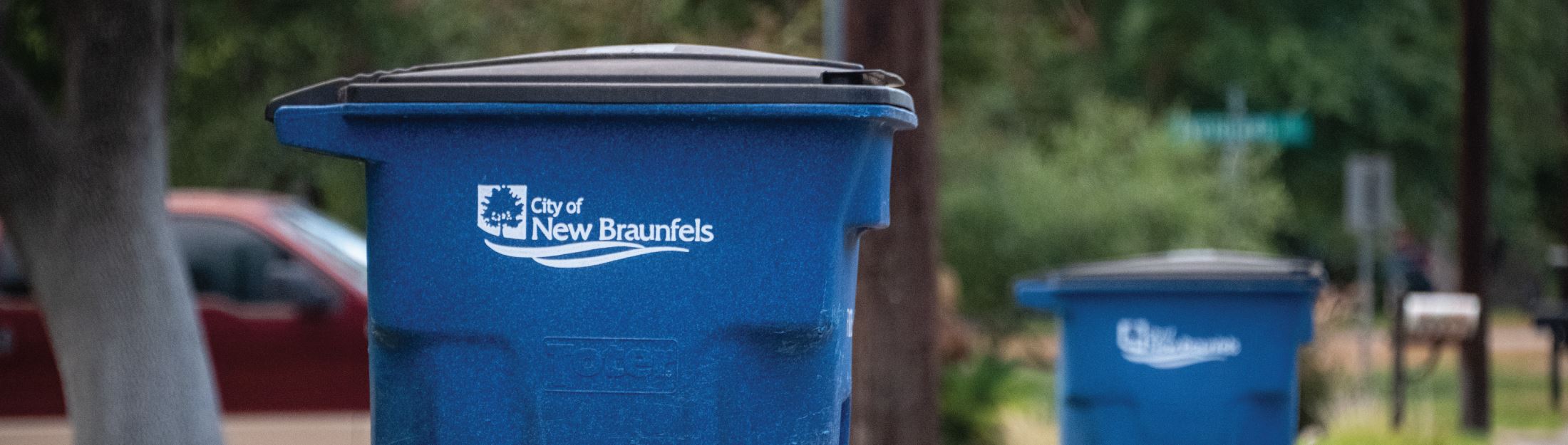 Two City of New Braunfels recycling bins sitting side by side