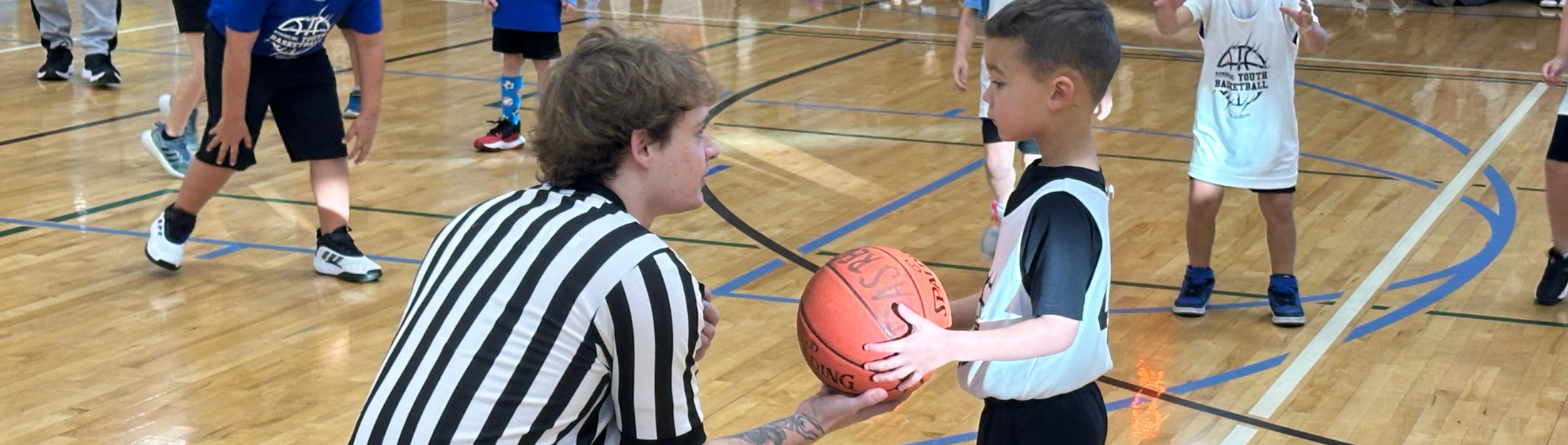 A referee hands a young boy a basketball at Das Rec
