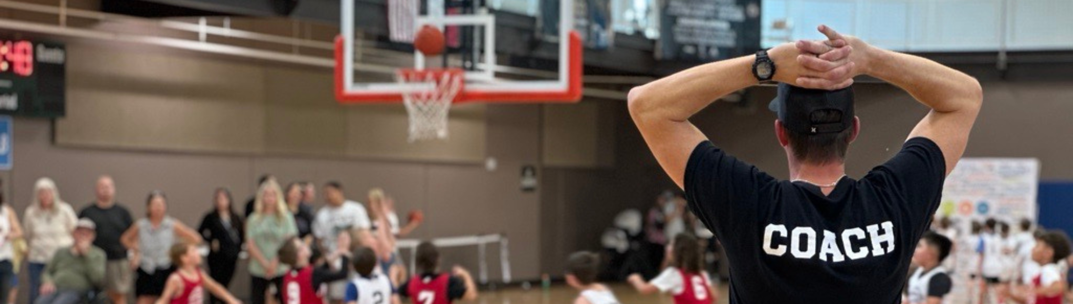A basketball coach looks on during a game at Das Rec