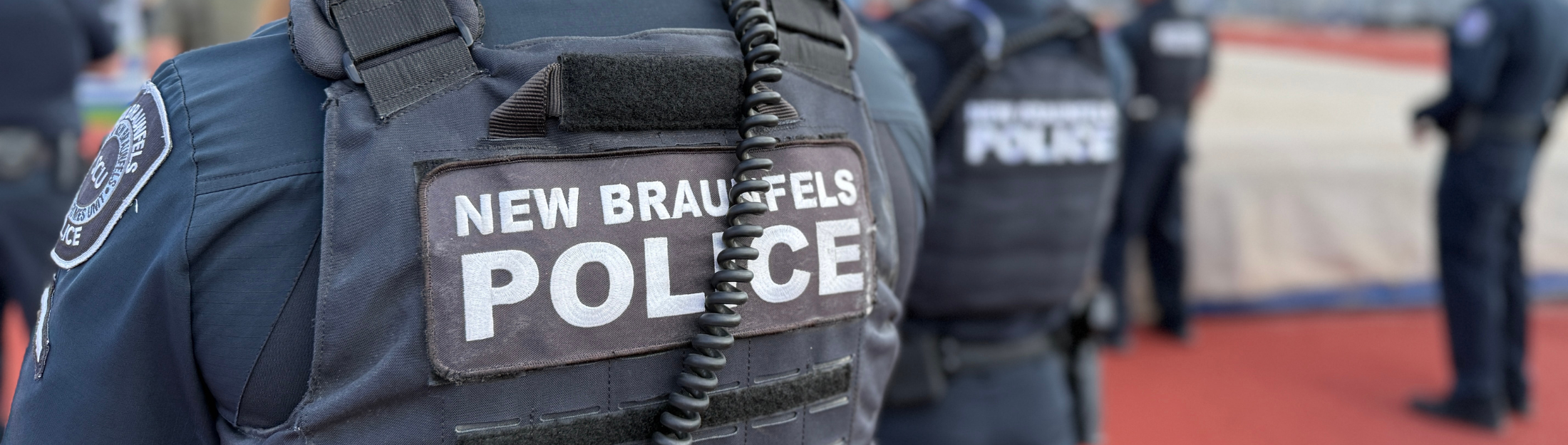 Close-up of New Braunfels Police officer in uniform with others standing in the background