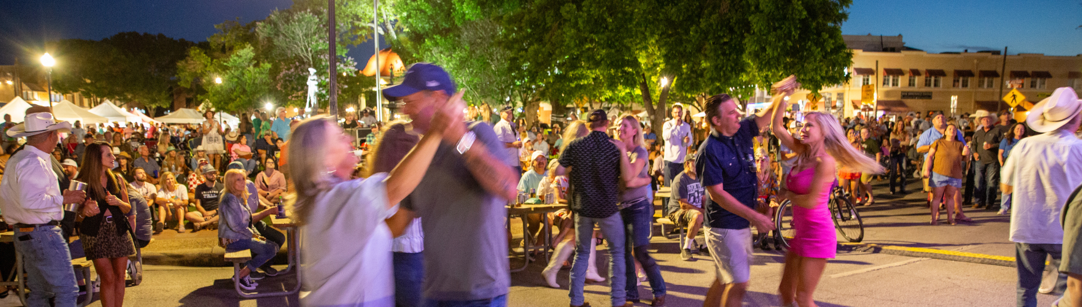 Couples dancing to music and some people are sitting on benches